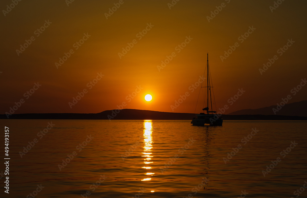 Beautiful sunset in the sea, sailing boat catamaran at anchor at night