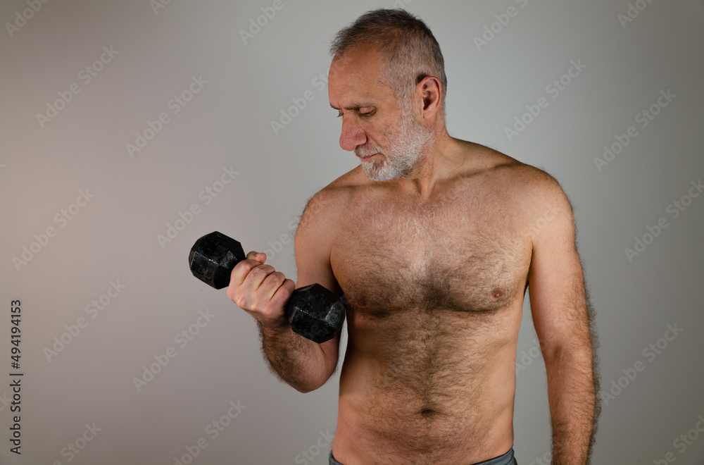 Portrait of shirtless adult man training with dumbbell against white background