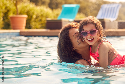 Laughing Mother And Daughter Wearing Sunglasses Having Fun In Swimming Pool On Summer Vacation photo