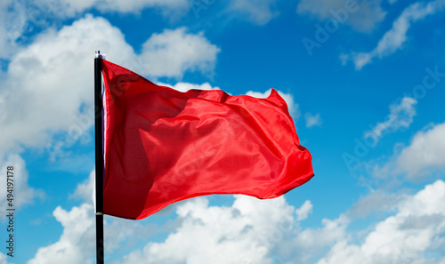 Vászonkép Red flag waving against blue sky