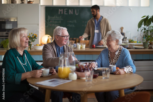 Group of cheerful seniors enjoying breakfast in nursing home care center.