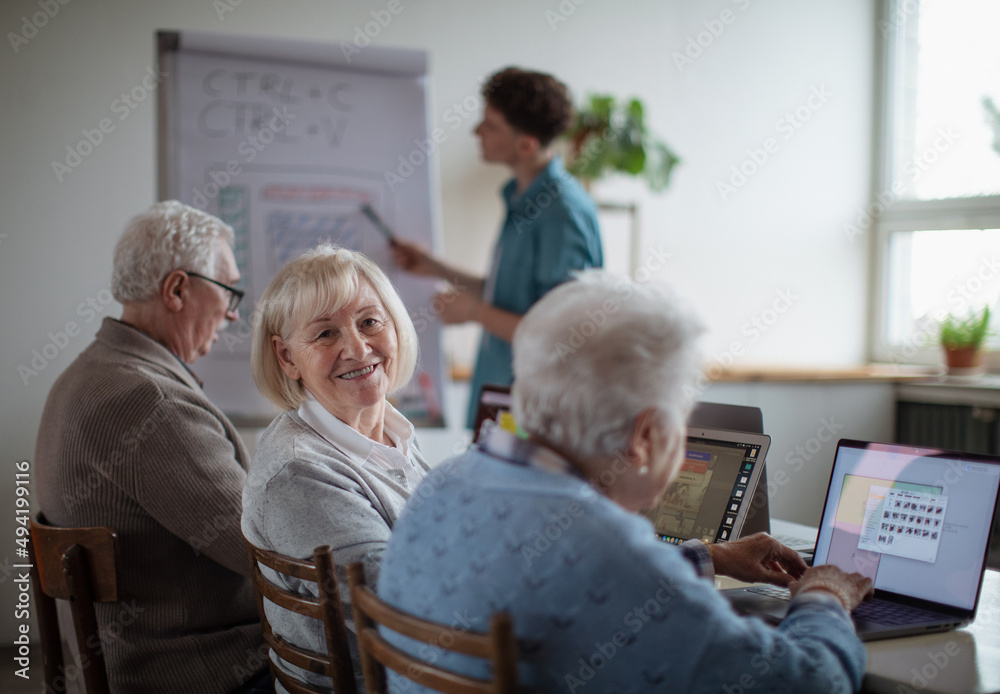 Obraz premium Senior group in retirement home with young instructor learning together in computer class