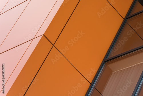 Geometric colored building facade elements with planes, lines and corners with light flare and reflections for an abstract background and texture of white, orange, gray colors. Place for text