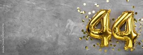 Yellow foil balloon number, number forty four concrete background. Greeting card with the inscription 44. Anniversary concept. for anniversary, birthday, new year celebration. banner photo