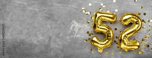 Yellow foil balloon number, number fifty two concrete background. Greeting card with the inscription 52. Anniversary concept. for anniversary, birthday, new year celebration. banner,