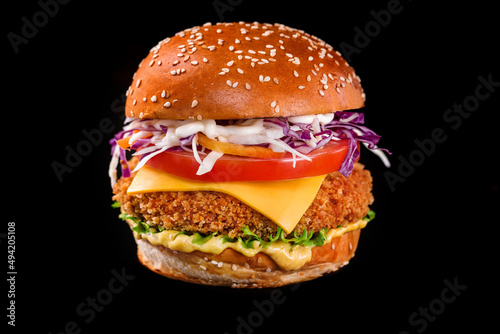 chicken cheeseburger with lettuce tomato on a black background