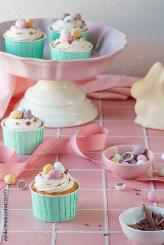 Easter egg food celebration image. Cupcakes, easter eggs, mini chocolate eggs and baking tools included in portrait frame. Pink and pastel colour spring colour theme.