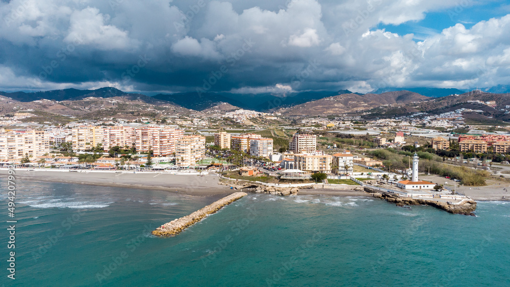 Fototapeta premium Drone perspective of costal city of Torrox situated in Malaga, Costa del Sol, Spain. Touristic travel destination. View of the promenade and beach area. The lighthouse of Torrox and the river.