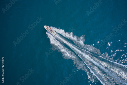 One boat on blue water drone view. Modern boat in motion making a trail on the water top view. Boat moving fast aerial view. © Berg