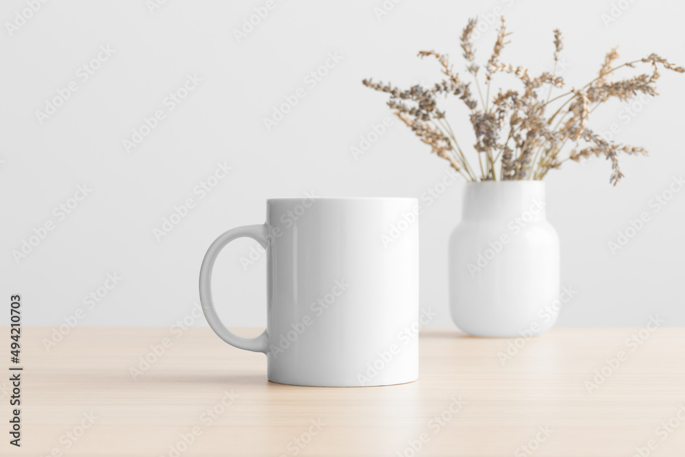 White mug mockup with a lavender decoration on the wooden table. White mug mockup with a lavender decoration on the wooden table.