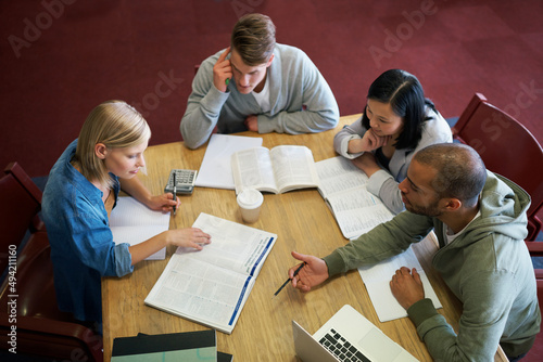 Cramming some last minute knowledge. A group of young people studying together in the library.