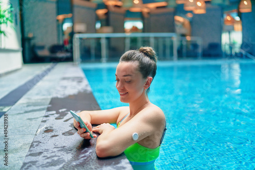 Active athletic fitness diabetic patient monitoring glucose level with remote sensor while training at swimming pool. Smart medical technology in diabetes treatment © Goffkein