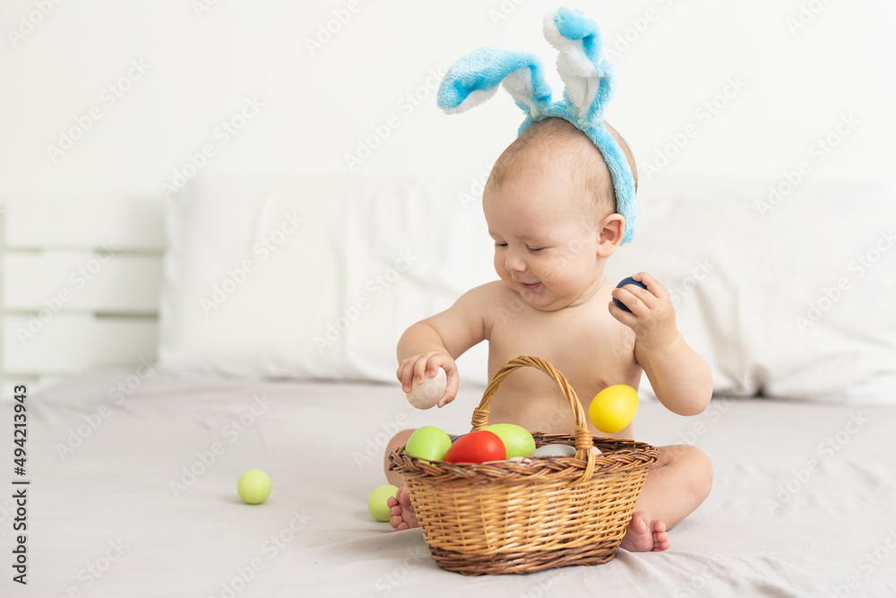 Portrait of a cute baby dressed in Easter bunny ears with a basket full of eggs