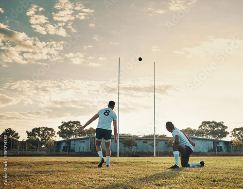 That was a master kick. Full length shot of two young rugby players training together on the field during the day.