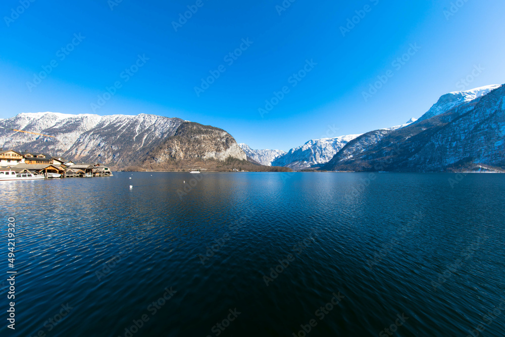 Panoramic view of the crystal-clear Lake Hallstatt. In the background the Dachstein glacier with a cloudless blue sky. Hallstatt, Salzkammergut, Upper Austria. Place for text.