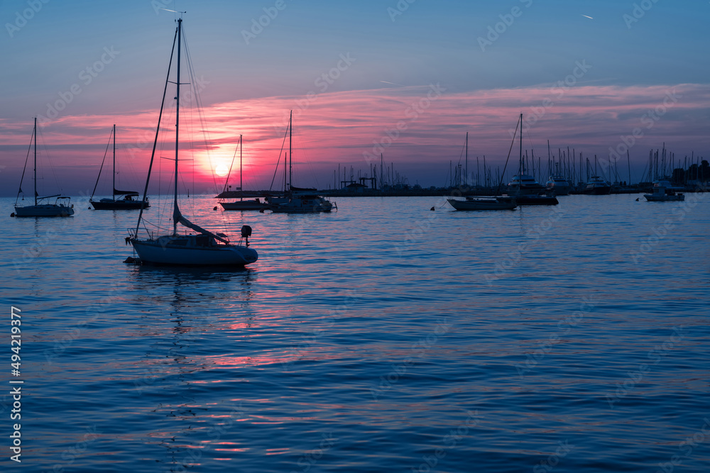 Sunrise on the seashore. In the silhouette of the ships in the harbor. Selective focus 