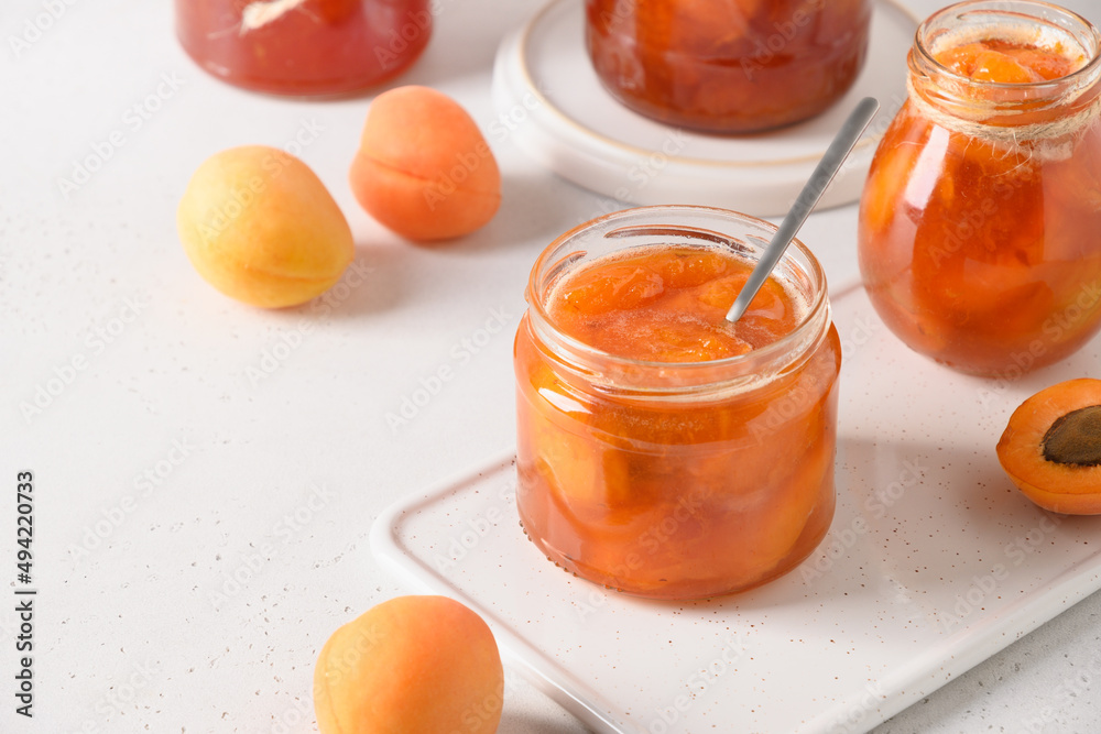 Apricot jam in glass jar on white background. Summer harvest and canned food. Copy space. Close up.