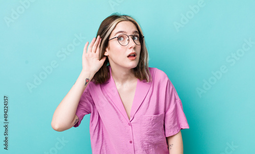 pretty caucasian woman smiling, looking curiously to the side, trying to listen to gossip or overhearing a secret photo