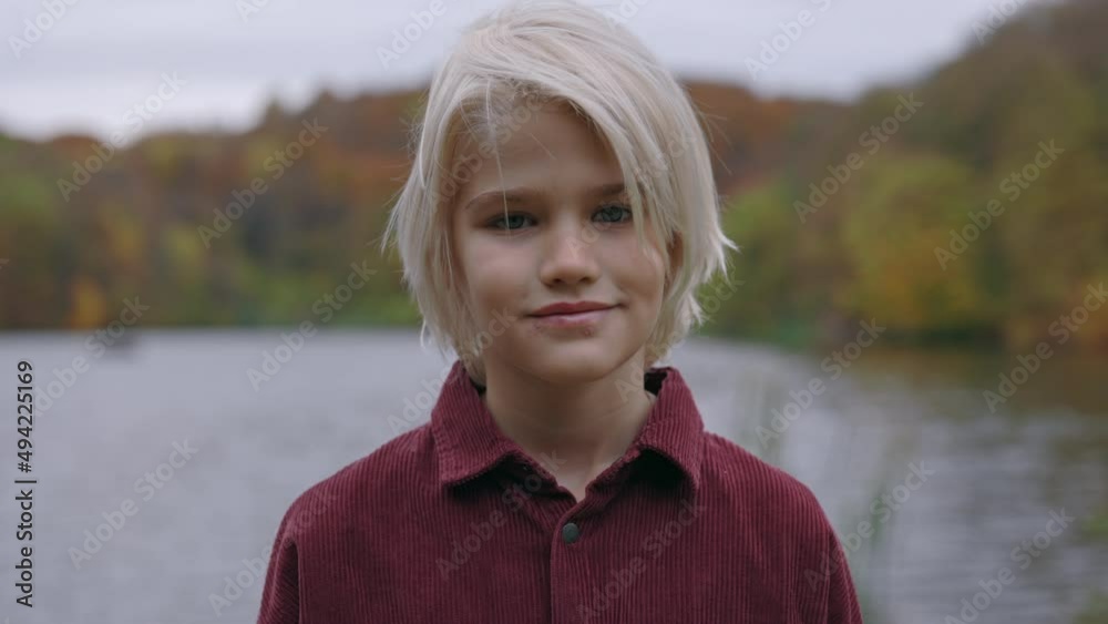 Portrait of handsome boy in casual wear posing on river bank