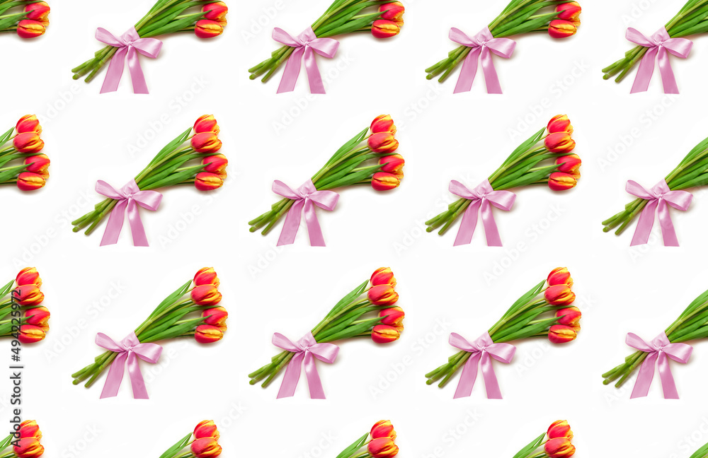 Beautiful yellow and red tulip flowers lie on a white background. Isolate, space for text, top view. Gift for a holiday to a woman and a girl. Pattern seamless Beautiful yellow and red tulip flowers lie on a white background. Isolate, space for text, top view. Gift for a holiday to a woman and a girl. Pattern seamless