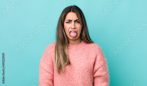 pretty hispanic woman feeling disgusted and irritated, sticking tongue out, disliking something nasty and yucky photo