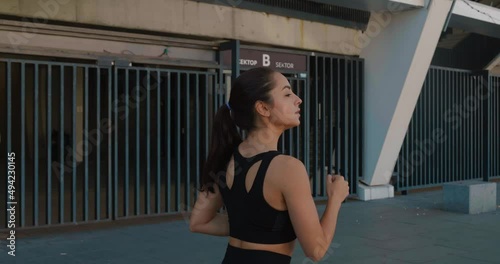 Athletic young woman jogging outdoors in slow motion. Fitness girl doing cardio workout, running in the morning on city streets