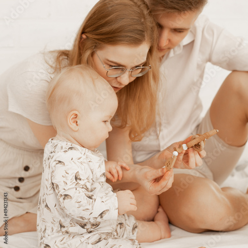 Young family spending time together, mother, father newborn baby. Showing wood toys, delayed psychological development. photo