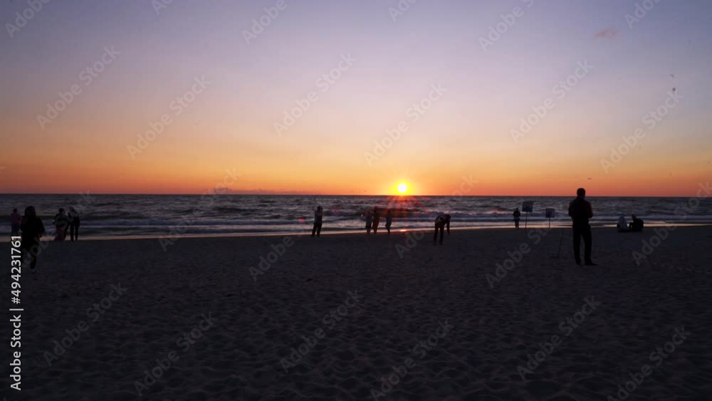people walking on the beach at sunset near the sea people walking on the beach at sunset near the sea