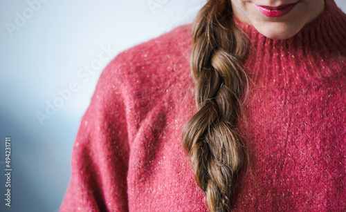 Woman with braid and lipstick wearing a pink warm soft glitter winter sweater