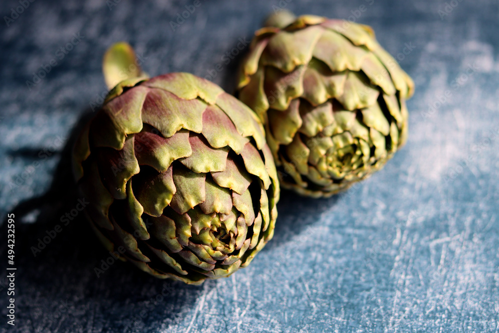 Obraz premium Close up photo of two artichokes on textured background with copy space. Beautiful artichoke flowers texture. Balanced diet concept.