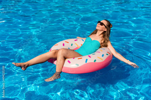 young woman in bikini swims on the inflatable water donut in the swimming pool