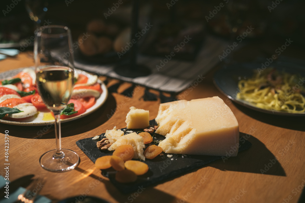 Cheese platter with cheeses, fruits, nuts, tomato and wine on wooden table