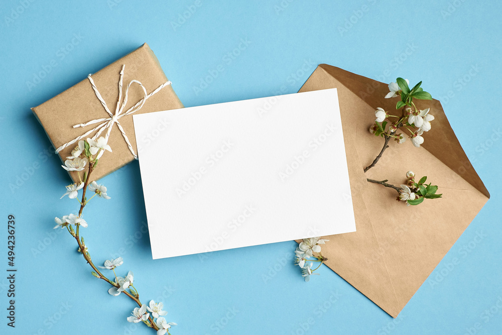 Greeting card mockup with gift, envelope and white flowers on blue background Greeting card mockup with gift, envelope and white flowers on blue background