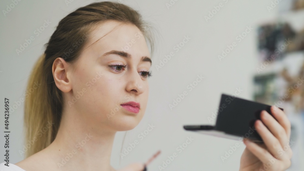 The girl paints her lips with lipstick. Close-up of the face. Macro photography of A Woman Wearing lipstick. The face macro. The girl looks in a small mirror The girl paints her lips with lipstick. Close-up of the face. Macro photography of A Woman Wearing lipstick. The face macro. The girl looks in a small mirror