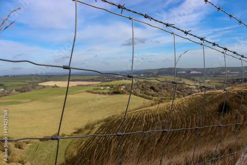 Beautiful pastoral view from countryside behind the wire fences. Hiking route. Unfocused natural landscape.