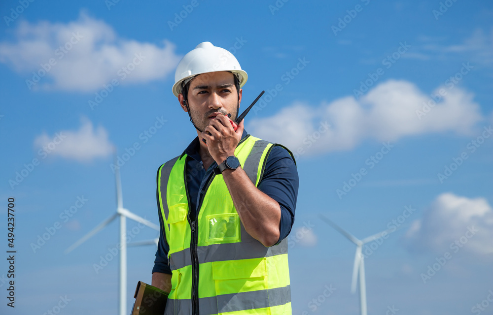 Young male engineer are using radio to communicate with engineers at renewable energy farm. Asian man wind turbine engineers working for electric power generation