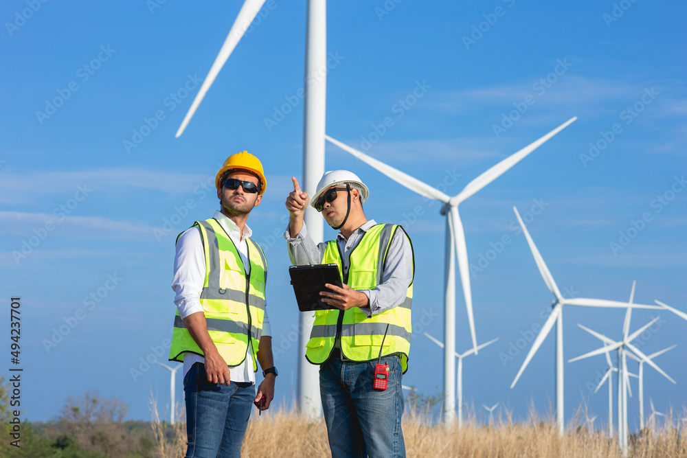 A team of Asian male engineers working together at wind turbine generator farm. A team of Asian male engineers working together at wind turbine generator farm.