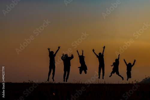 The silhouette of children jumping and playing happily in the mountains at sunset