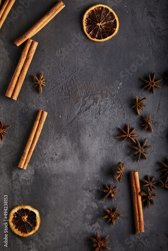 Spices, cinnamon, dried orange, anise on a black, old textured background. Space for text.