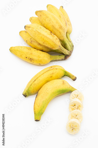 whole and slices bananas over on white background, top view