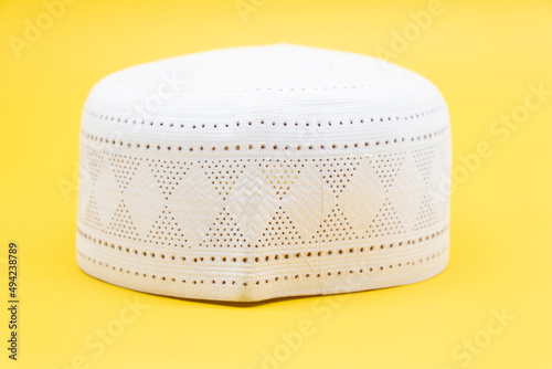 white skull-cap usually worn by Muslim men, its a symbol of muslim Sunnah over on yellow background