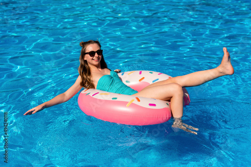 young woman in bikini swims on the inflatable water donut in the swimming pool.