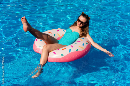young girl in bikini swims on the inflatable water donut in the swimming pool