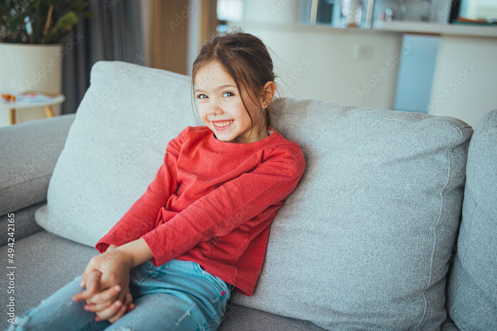 Beautiful little girl portrait at home. Cute child smiling and looking at camera. Funny little girl with blonde hair laughing,looking in camera with satisfied expression, posing for family photo. Beautiful little girl portrait at home. Cute child smiling and looking at camera. Funny little girl with blonde hair laughing,looking in camera with satisfied expression, posing for family photo.