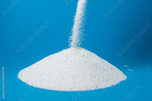 Laundry detergent on a blue background. Washing powder sprinkled on a pile of washing powder. Household chemicals