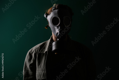Photo of a military man in a gas mask, apocalypse, nuclear weapons, atomic explosion of a station, chemical and nuclear weapons protection. Girl in a mask on a green background, war. © MoreThanProd