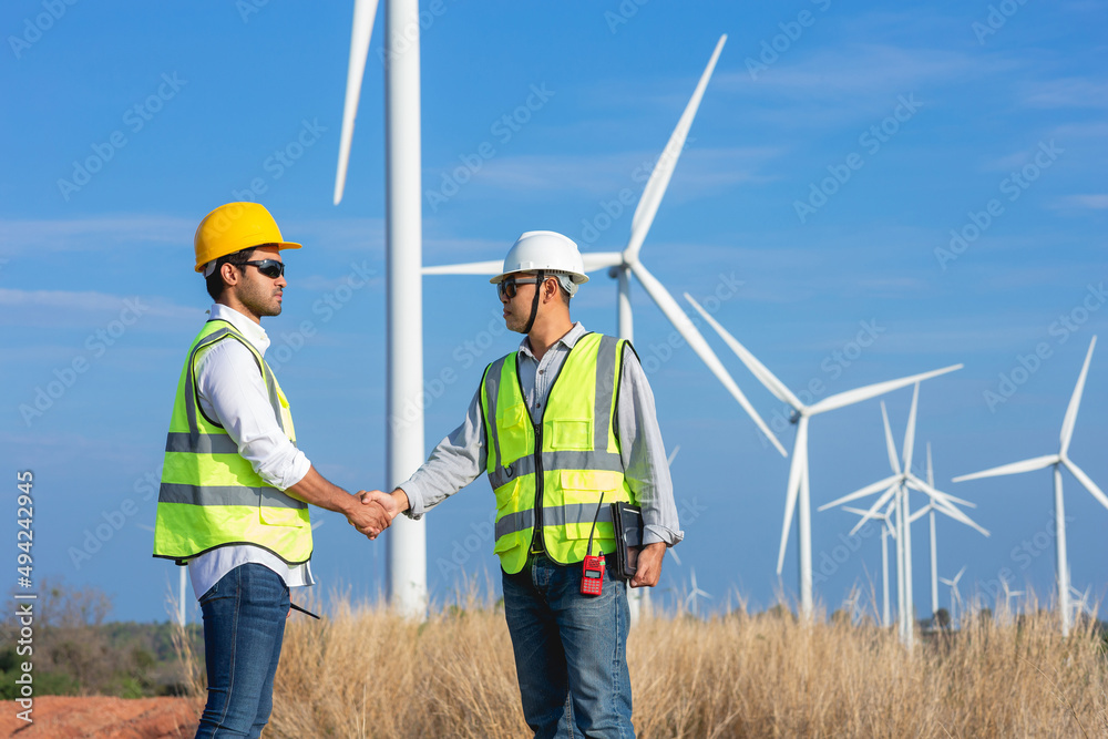 Two man Asian wind turbine engineers shaking hands after successful work together.