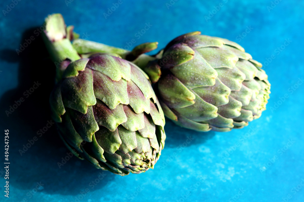 Fototapeta premium Still life with fresh artichoke flowers. Close up photo of beautiful natural pattern. Eating healthy concept. 