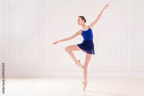 professional student ballerina doing pointe shoes in a beautiful white room