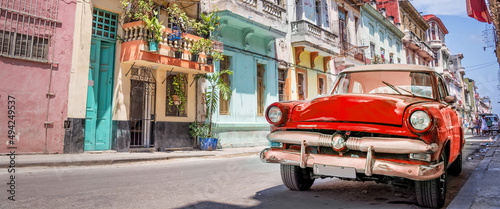 Vintage classic red american car in a colorful street of Havana, Cuba. Panoramic travel web banner. © Delphotostock